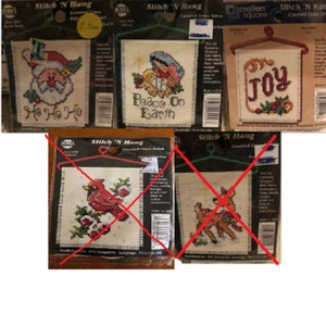 Pode incluir: Um conjunto de seis kits de ponto cruz contados com temas natalinos. Os kits incluem um Papai Noel com o texto "Ho Ho Ho", uma cena da Natividade com o texto "Peace on Earth", uma rena, um cardeal, um veado e um desenho com a palavra "Joy".