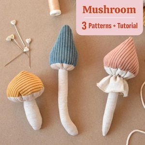 May include: Three plush mushroom toys with different colored tops: blue, pink, and yellow. The mushrooms have white fabric stems and are made with a ribbed fabric. The image includes the text "Mushroom 3 Patterns + Tutorial".