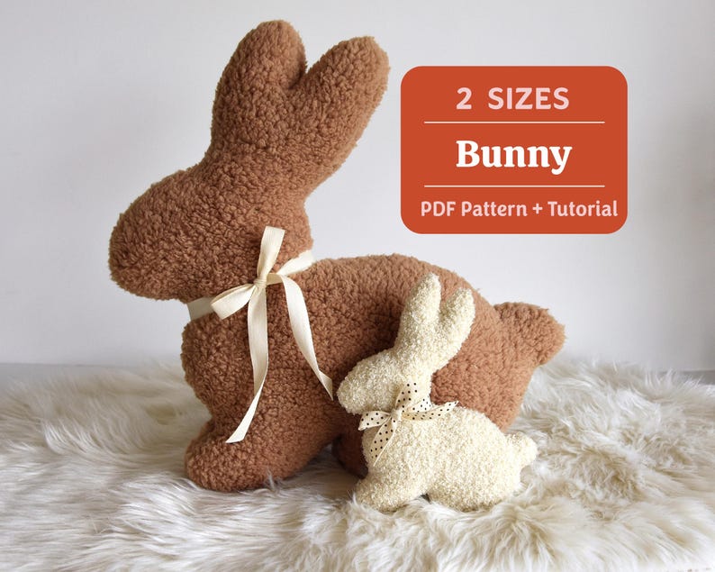 May include: Two plush bunny toys, one brown and one white, with a white ribbon tied around the brown bunny's neck. The text "2 SIZES Bunny PDF Pattern + Tutorial" is displayed on a red background.
