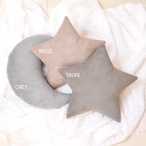 Op de afbeelding: Drie decoratieve kussens in de vorm van een halve maan en een ster. Het maankussen is grijs, het sterkussen is taupe en het andere sterkussen is beige.