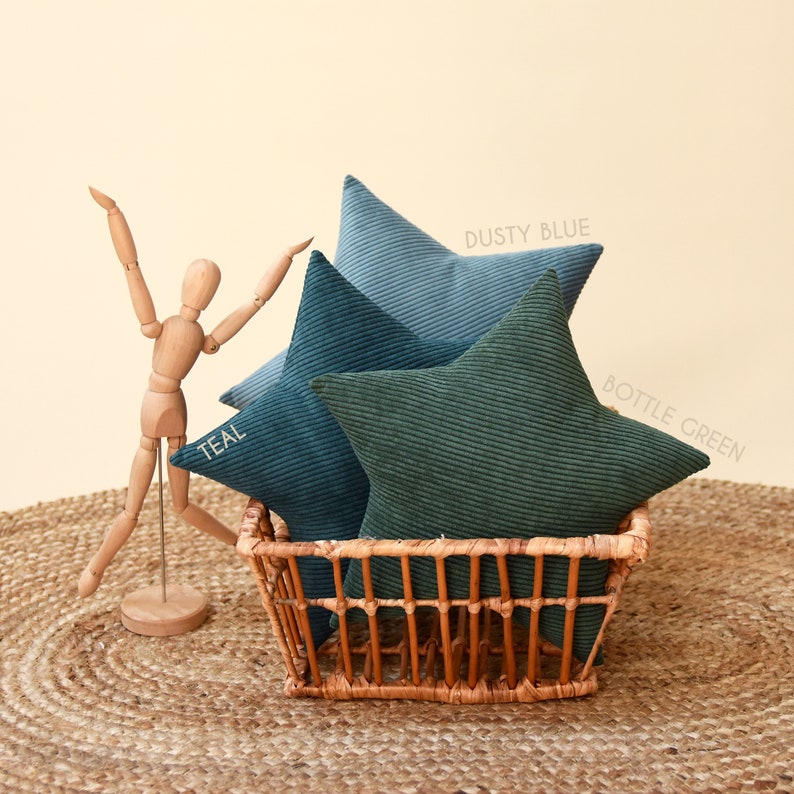 Three star shaped pillows displayed in a wicker basket. Made out of thick and very soft corduroy. First decorative pillow is in bottle green color, next in teal and the last one in dusty blue. Together they make a adorable matching set.