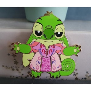 May include: Green Stitch character wearing a pink and purple dress with floral patterns. The character has a large, green head with a wide mouth and large, black eyes. The character is standing on a white background with gold stars.