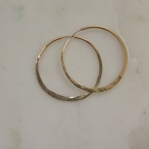 May include: A pair of gold hoop earrings with a hammered texture.