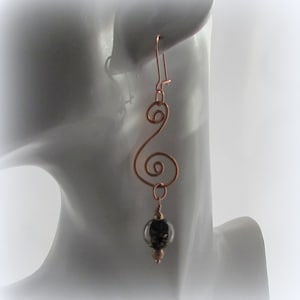 May include: Copper wire earrings with a swirl design and a black and silver glass bead.