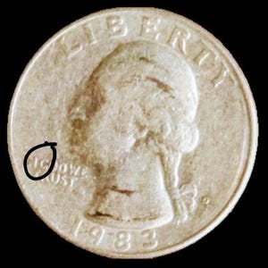 May include: A silver US quarter dollar coin with the year 1983 and the words "LIBERTY" and "IN GOD WE TRUST" inscribed on it. The coin features a profile of a woman's head.