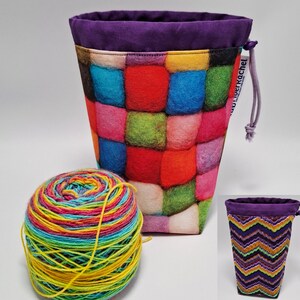 May include: A colorful yarn storage bag with a patchwork design in shades of red, blue, green, and pink. The bag has a purple rim and drawstring closure. A ball of rainbow-colored yarn sits next to the bag, showcasing a craft theme.