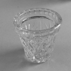 May include: A clear glass vase with a cut glass design. The vase has a wide mouth and a narrow base.