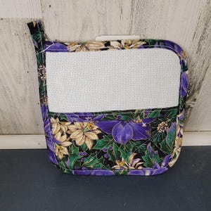 May include: Purple and gold floral print pot holder with a white fabric insert. The pot holder has a loop for hanging.