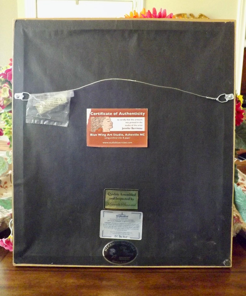 May include: The back of a framed artwork with a certificate of authenticity from Blue Wing Art Studio, Asheville NC. The certificate states that the artwork was prepared in the studio of the artist Jennifer Barrineau. The artwork is also labeled as "Quality Assembled and Inspected by Tri-Guard".