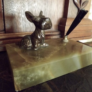 May include: A vintage desk set with a bronze sculpture of a Scottish terrier on a green marble base. A black pen holder is attached to the base.
