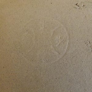 May include: Close-up of a light brown ceramic surface with a faint, circular mark in the center.