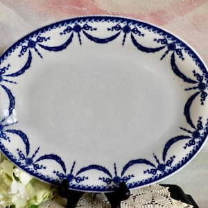 May include: A white oval serving platter with a blue and white floral design around the edge.