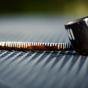 May include: A wooden smoking pipe with white accents and the word "Aviv" inscribed on the side. The pipe is lying on a black textured surface.