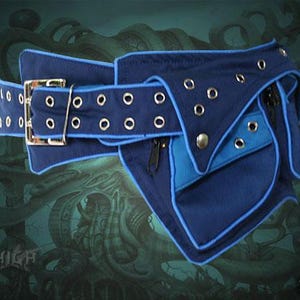 May include: A blue and black canvas belt with a large pocket and multiple zippered compartments. The belt has a buckle and grommets along the edge.