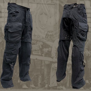 Pu&ograve; includere: Pantaloni cargo neri con pi&ugrave; tasche e fibbie. I pantaloni hanno un design unico con una patta sul retro.