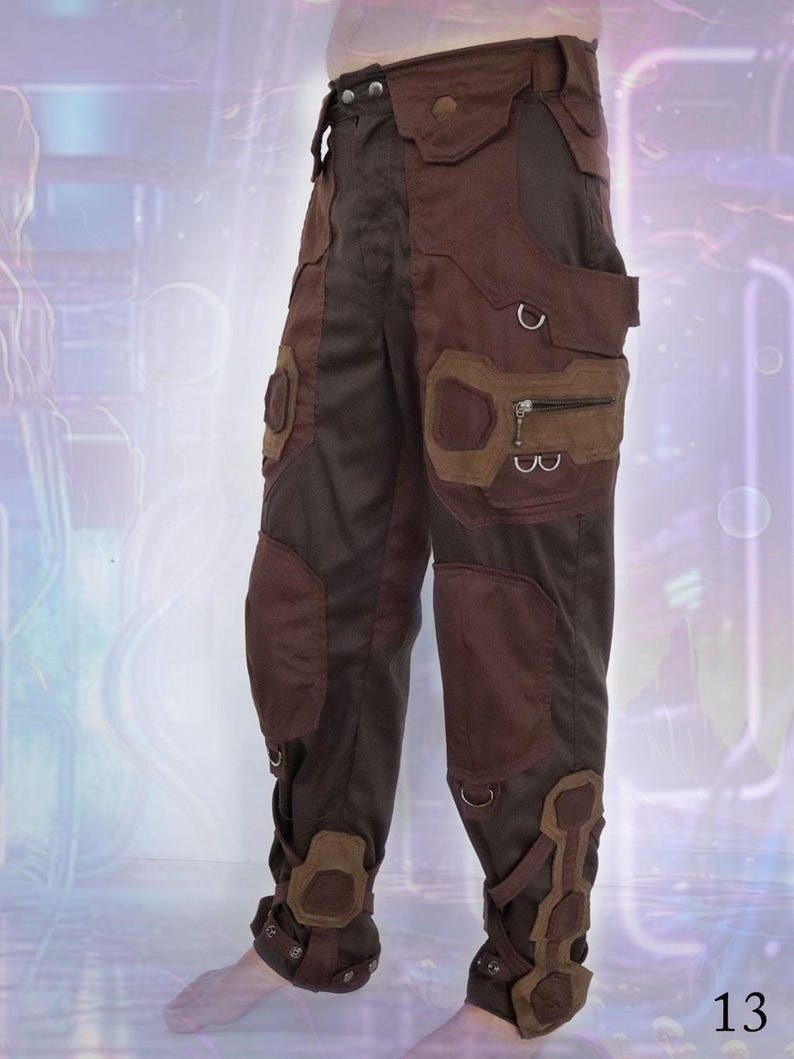 K&ouml;nnte beinhalten: Braune und schwarze Cargohose mit mehreren Taschen und Riemen. Die Hose hat ein einzigartiges Design mit einer Mischung aus Texturen und Materialien.