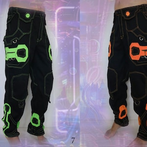 K&ouml;nnte beinhalten: Zwei Paar schwarze Cargohosen mit kontrastierenden Neon-Gr&uuml;n- und Orangeakzenten. Die Hosen haben mehrere Taschen und ein einzigartiges Design mit geometrischen Formen.
