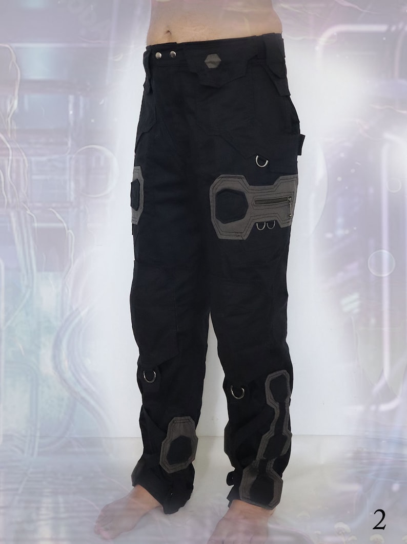 K&ouml;nnte beinhalten: Schwarze Cargohose mit grauen Akzenten und mehreren Taschen. Die Hose hat ein einzigartiges Design mit verst&auml;rkten Knien und einer Rei&szlig;verschlusstasche am rechten Bein.