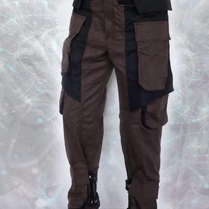 Brown cargo pants with black accents and multiple pockets. The pants have adjustable straps at the bottom of the legs.