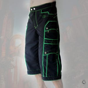 May include: Black cargo shorts featuring vibrant neon green contrast stitching and piping along the seams and pockets. The shorts include multiple utility pockets with silver-toned metal rivets and a zippered compartment on the left side.