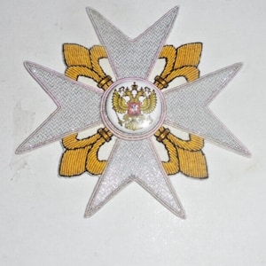 May include: A white embroidered cross with gold accents and a central round emblem featuring a double-headed eagle with a red shield.