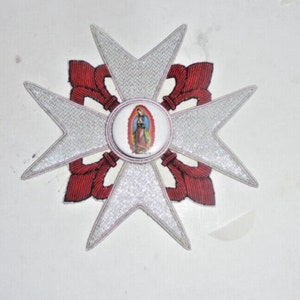 May include: A white embroidered star with red embroidered accents and a round image of the Virgin Mary in the center.
