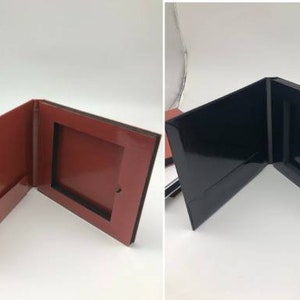 May include: Four different colored boxes with a square opening in the front. The boxes are open and folded back to reveal the opening. The colors are silver, red, black, and gold.