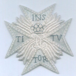 May include: A silver embroidered cross with the words "INST", "TI", "TOR", and "TV" around the edges. The cross is decorated with a crown and wings.