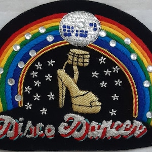 May include: A black felt patch with a rainbow, a silver disco ball, a gold high heel shoe, and the text "Disco Dancer".