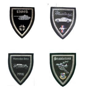 May include: Eight embroidered patches with different designs. The patches are black, green, and blue with silver and white embroidery. The patches feature a Ferrari, a tank, a Mustang, a drone, a Chevrolet, a Mercedes Benz, a bomber plane, and a Belial logo.