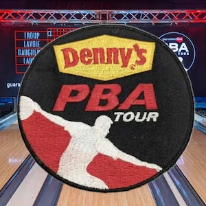 May include: A black and red Denny's PBA Tour patch featuring a bowler in action. The patch is circular and set against a bowling alley background with a scoreboard and lighting rig.