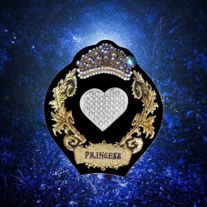 May include: A black velvet patch with gold embroidery and a silver heart with rhinestones. The patch has a crown with rhinestones and the word "Princess" written on it.