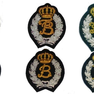 May include: Six embroidered patches with a crown and a letter in the center. The patches are black with silver and gold embroidery. The letters are R, B, RL, H, B, and X.