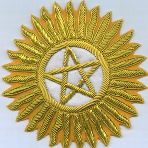 May include: A gold embroidered patch with a white five-pointed star in the center surrounded by a sunburst design.