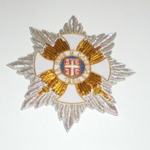 May include: A white and gold embroidered star-shaped patch with a red and white cross in the center. The cross has a small shield with a red cross on it. The text "1814" is visible on the shield.