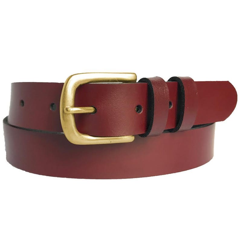 Puede incluir: Un cintur&oacute;n de cuero burdeos con una hebilla dorada. El cintur&oacute;n tiene un dise&ntilde;o cl&aacute;sico con una hebilla rectangular y dos trabillas. El cuero parece liso y el cintur&oacute;n est&aacute; curvado, lo que sugiere que es flexible y est&aacute; listo para usar.