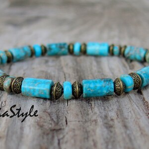 Peut inclure: Un bracelet composé de perles turquoise et de laiton. Les perles sont rectangulaires et présentent un motif marbré.