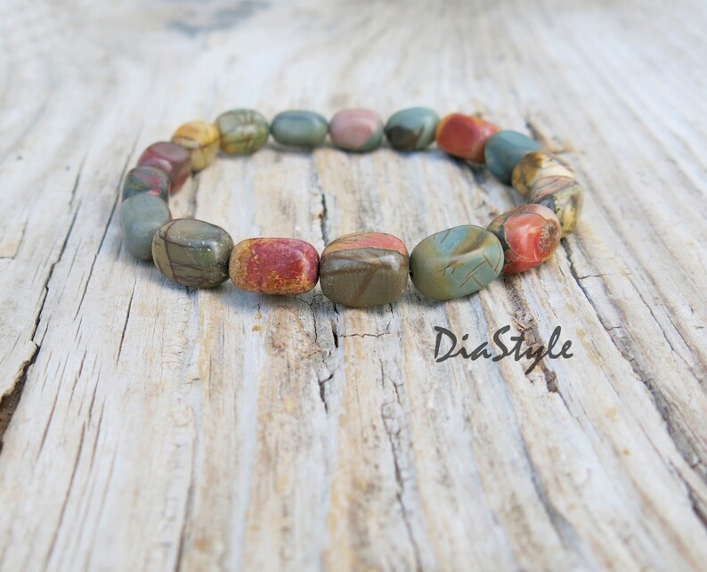 May include: A bracelet made of colorful, patterned stones. The stones are oval-shaped and have a smooth, polished finish. The bracelet is on a wooden surface.