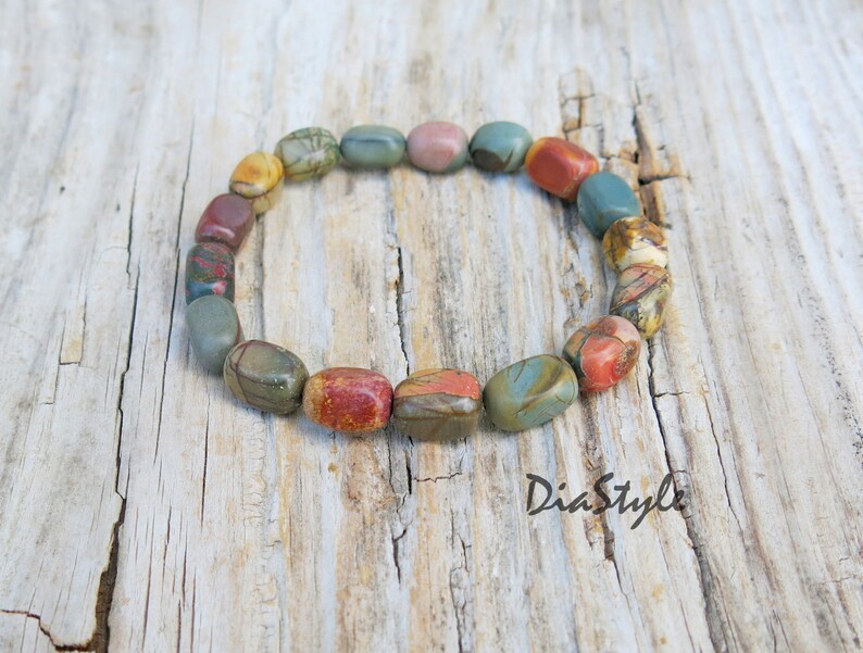 May include: A bracelet made of colorful, oval-shaped stones. The stones are a mix of brown, red, green, and white.