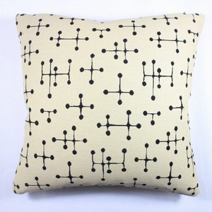 May include: A cream-colored throw pillow with a black geometric pattern. The pattern is made up of small circles connected by lines.