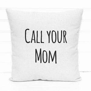 May include: Square white throw pillow with the text "CALL YOUR MOM" in black, centered on the front. The pillow is made of a soft fabric and is placed against a white background.