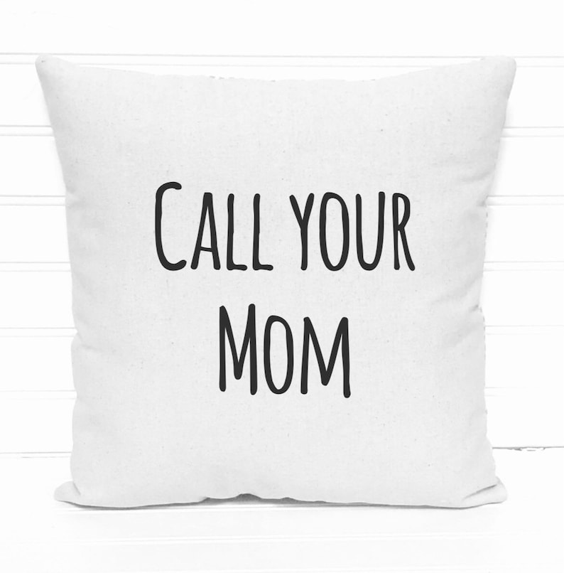 May include: Square white throw pillow with the text "CALL YOUR MOM" in black, centered on the front. The pillow is made of a soft fabric and is placed against a white background.