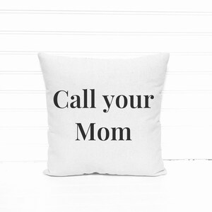 May include: Square white throw pillow with the text "Call your Mom" in black, centered on the front. The pillow is made of a soft, textured fabric and is displayed against a white background.