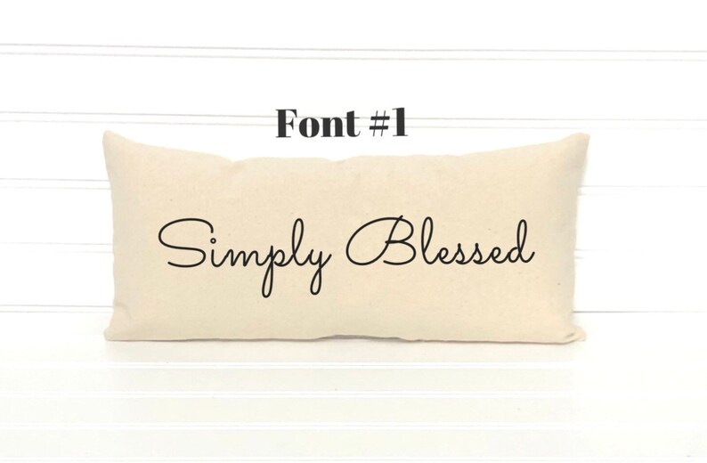 May include: A beige pillow with the text "Simply Blessed" in a cursive font.