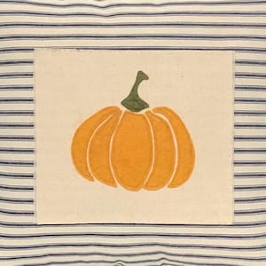Puede incluir: Un coj&iacute;n cuadrado con una base de tela color crema y finas rayas horizontales azul marino. Centrado en el coj&iacute;n hay un parche rectangular de tela color blanco roto que muestra una aplicaci&oacute;n de calabaza naranja con un tallo verde oscuro.