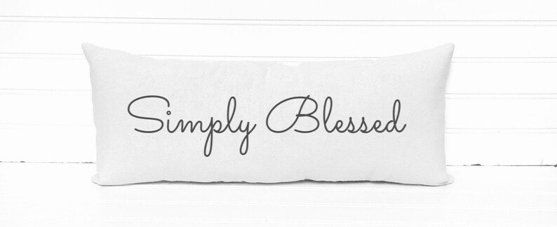 May include: White rectangular pillow with the text "Simply Blessed" in black cursive script.
