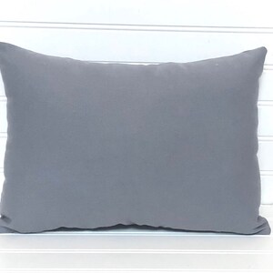 May include: A plain gray throw pillow with a soft, smooth fabric. The pillow is rectangular and has a subtle sheen.