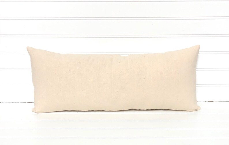 May include: A plain, off-white rectangular pillow with a smooth, linen-like fabric.
