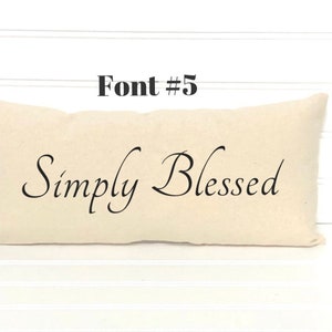 May include: A beige pillow with the text "Simply Blessed" in a cursive font.