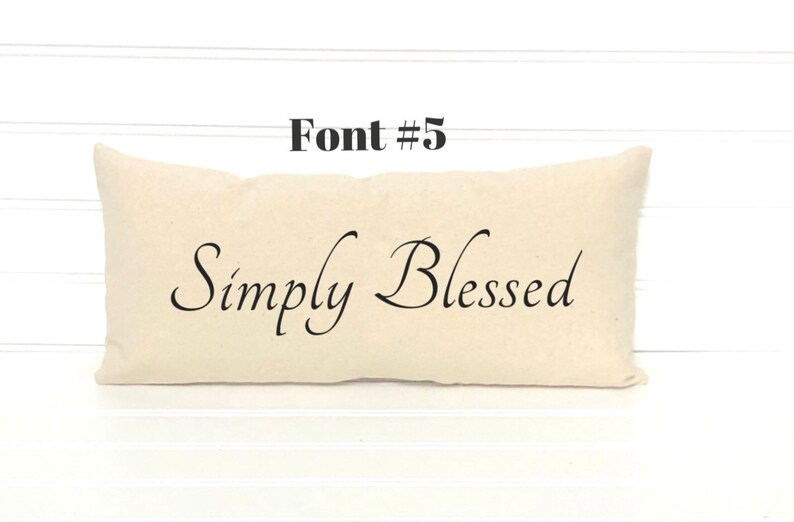 May include: A beige pillow with the text "Simply Blessed" in a cursive font.